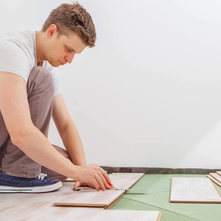 Man installing vinyl flooring in home