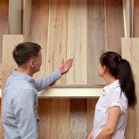 Salesperson showing customer popular laminate floors available at Dolphin Carpet