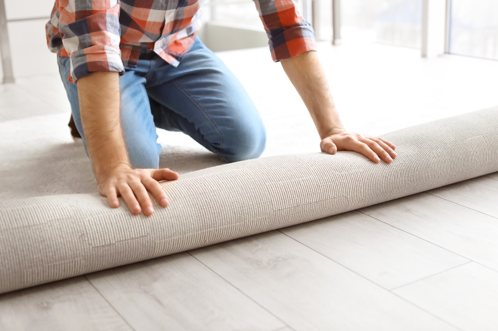 Man rolling out new carpet flooring in room carpet installation | Dolphin Carpet & Tile