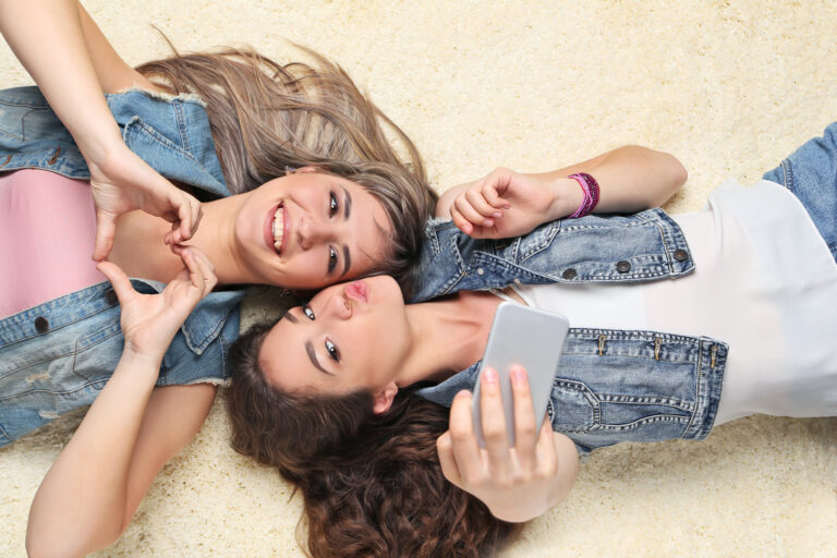Two young woman making selfie laying on carpet | Dolphin Carpet & Tile